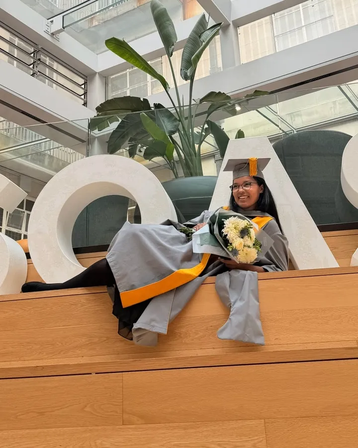 Ashleigh in graduation gown and cap at SOAS, holding flowers